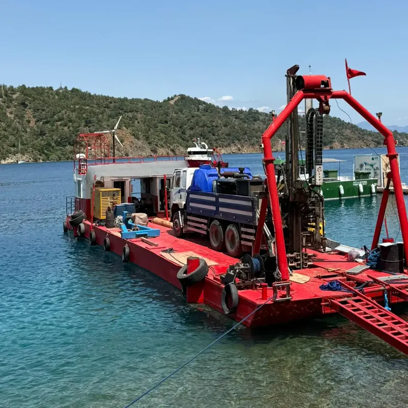 Truck-mounted drilling rig performing offshore drilling from a floating platform anchored in a bay