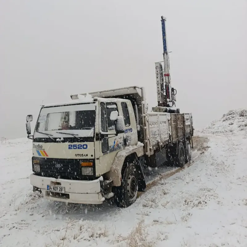 Truck-mounted drilling rig fieldwork in falling snow