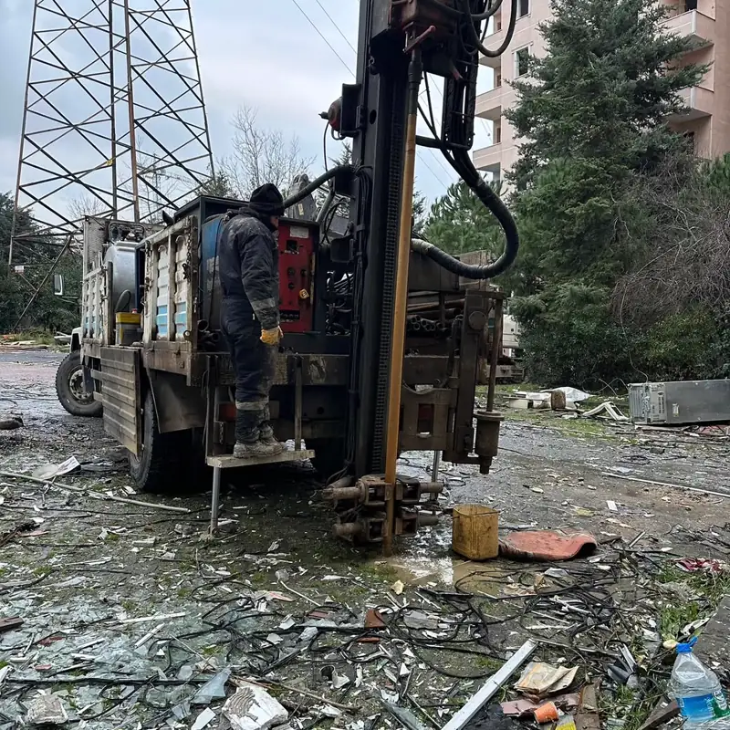 Truck-mounted drilling rig and operator working around an existing building